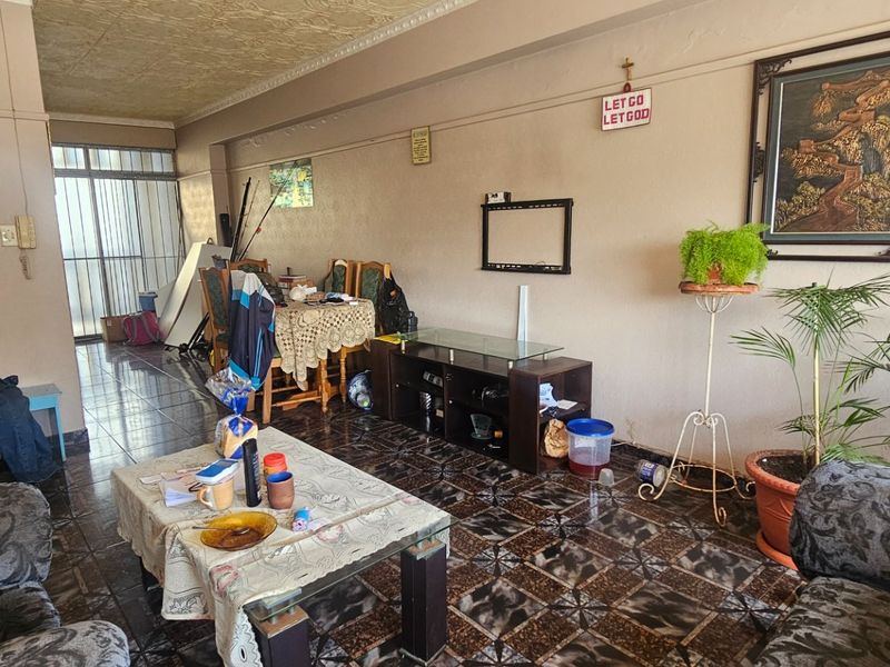 An open-plan living and dining area featuring tiled flooring, coved ceilings, and a sliding glass door leading to an outdoor space.