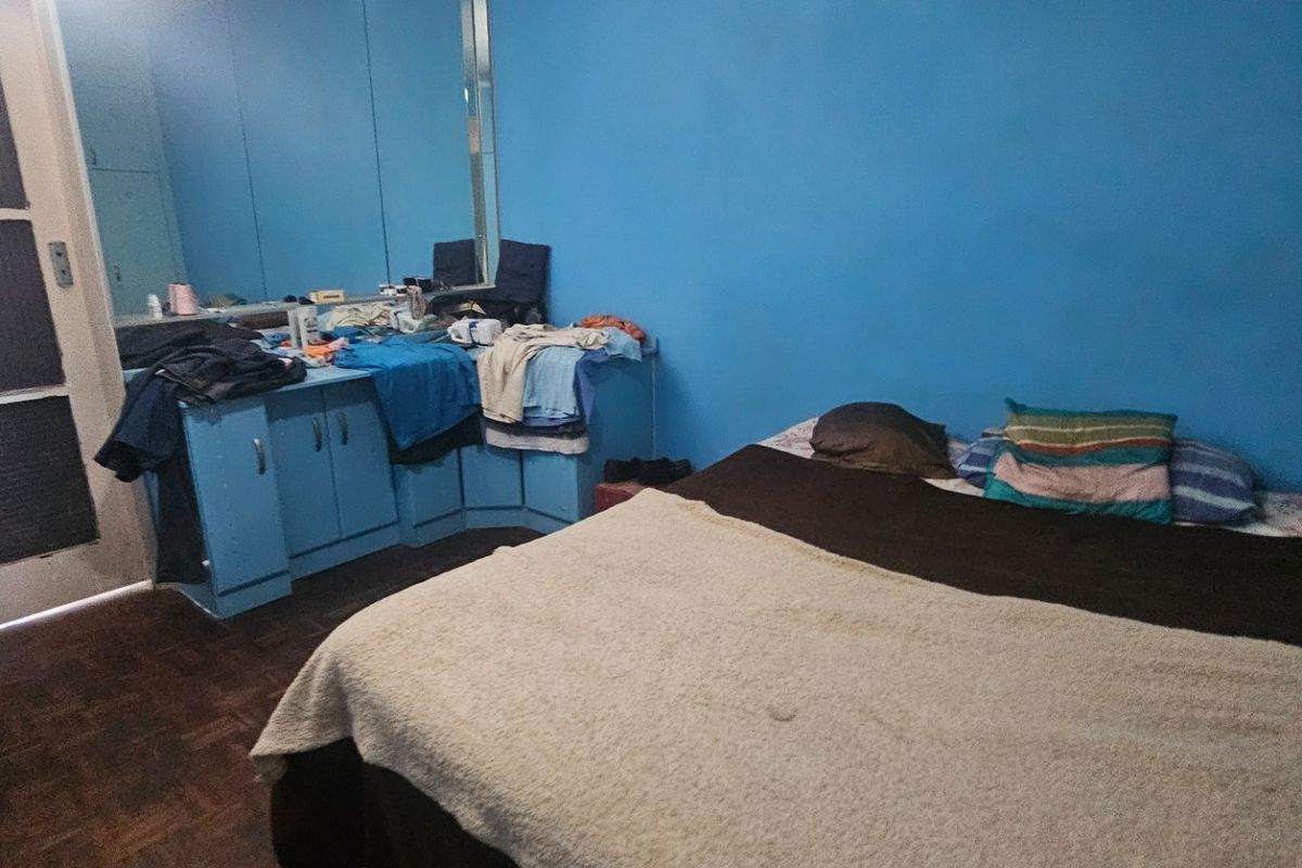 A bedroom featuring parquet flooring, built-in cupboards with integrated mirrors, and blue painted walls.