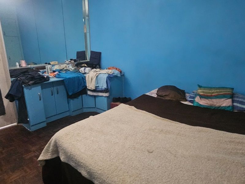 A bedroom featuring parquet flooring, built-in cupboards with integrated mirrors, and blue painted walls.