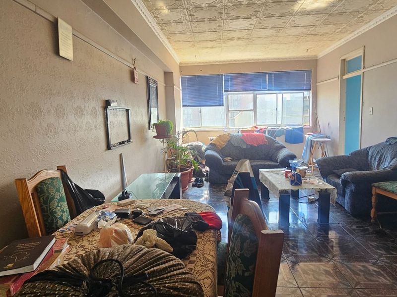 Open-plan living and dining area featuring tiled flooring, textured ceiling, and large windows providing natural light.