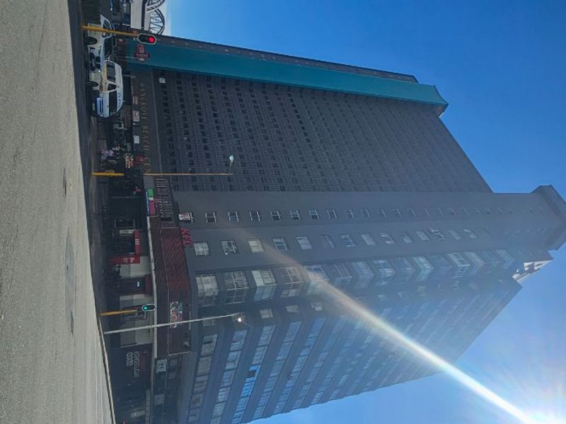 A low-angle street view of a high-rise apartment building featuring commercial retail space on the ground level.