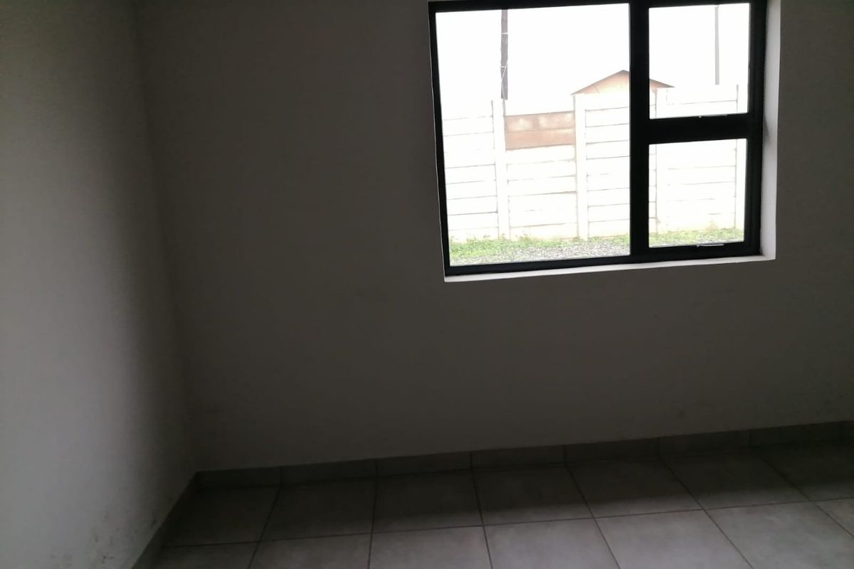 An empty bedroom featuring tiled flooring and an aluminium window frame, presenting a blank canvas for potential industrial or office use.