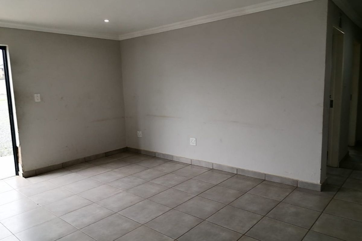 An empty living area featuring neutral tiled flooring, recessed lighting, and cove cornicing, presenting a blank canvas ready for customization.