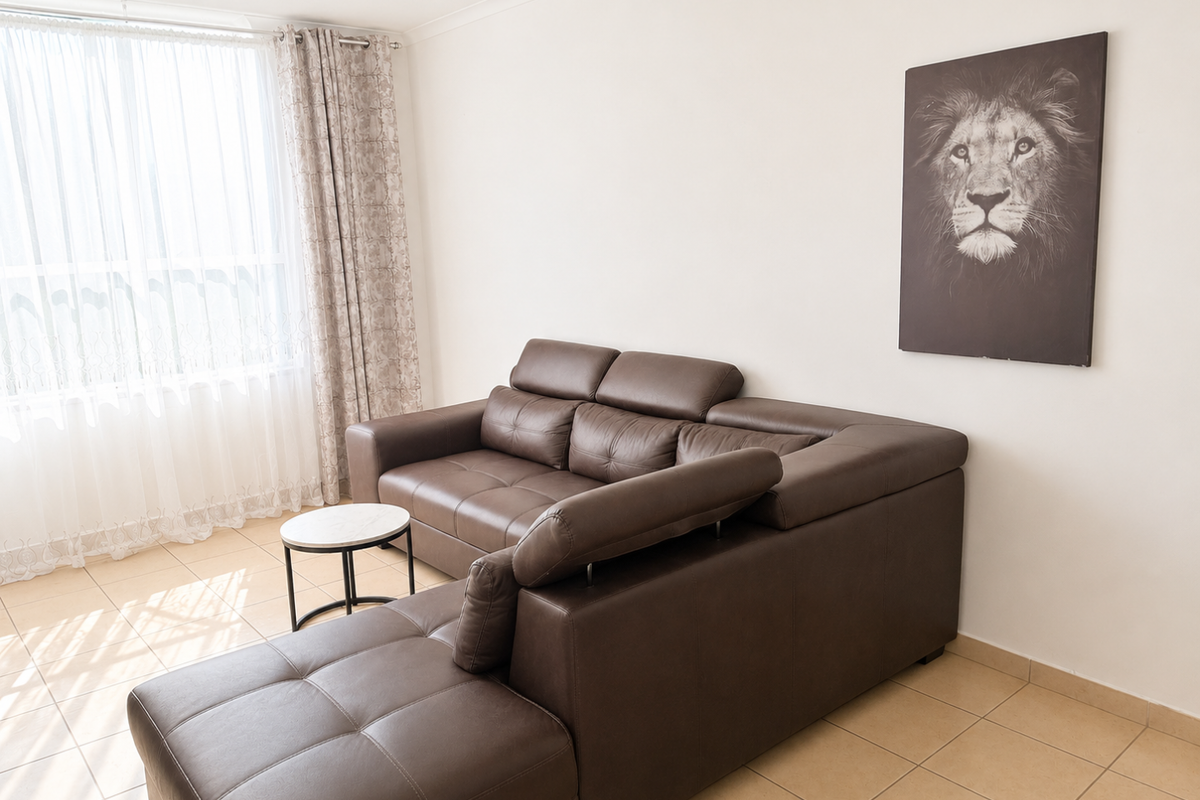 A bright living room featuring neutral tiled flooring and coving, with natural light entering through a large window.