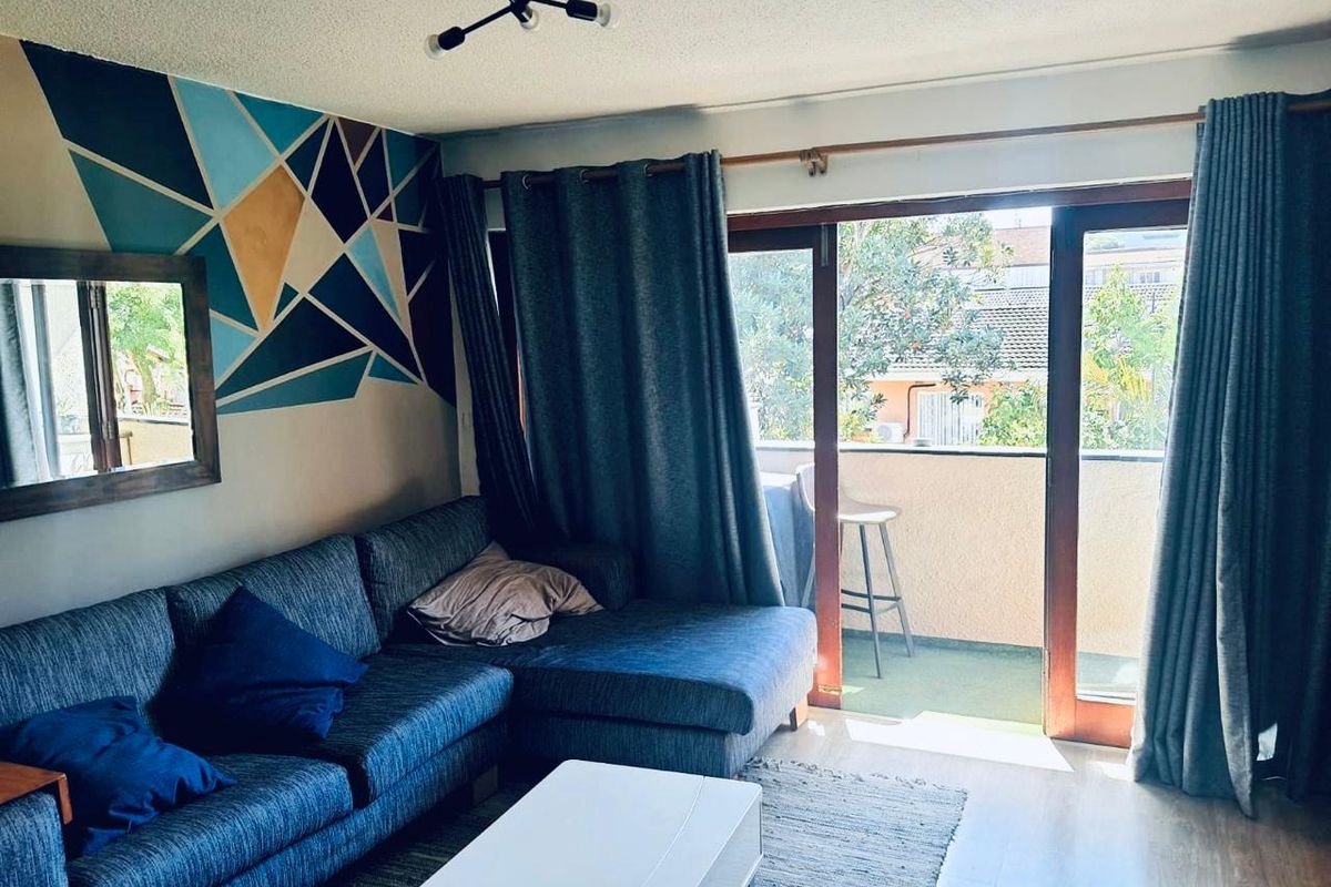 Living room featuring laminate flooring and large sliding glass doors providing access to a private balcony.