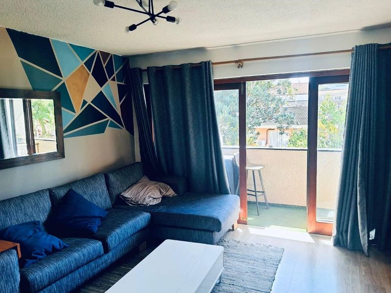 Living room featuring laminate flooring and large sliding glass doors providing access to a private balcony.