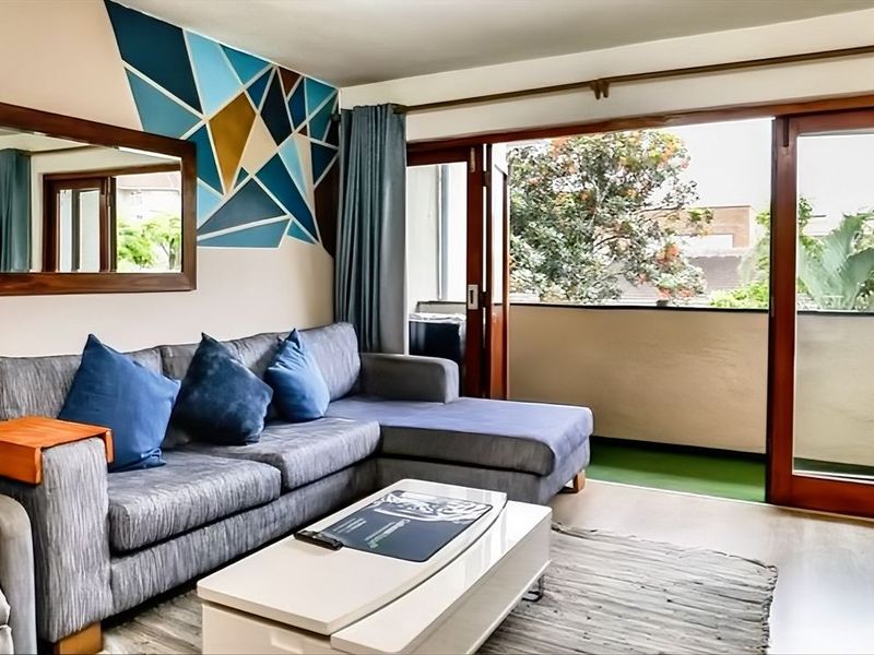 A comfortable living room featuring laminate flooring and large sliding glass doors that open onto a private balcony.