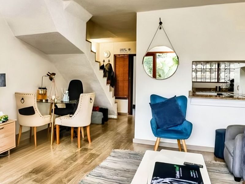 Open-plan living area featuring laminate flooring, a staircase, and a convenient pass-through window connecting to the kitchen space.