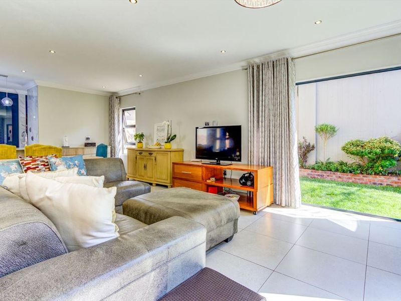 A bright and spacious living room featuring tiled flooring, recessed lighting, and a large sliding glass door providing direct access to the garden.