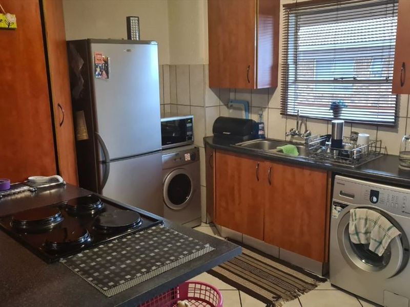 Functional kitchen featuring built-in cabinetry, laminate countertops, a tiled backsplash, and a built-in hob, offering a practical layout for daily meal preparation.