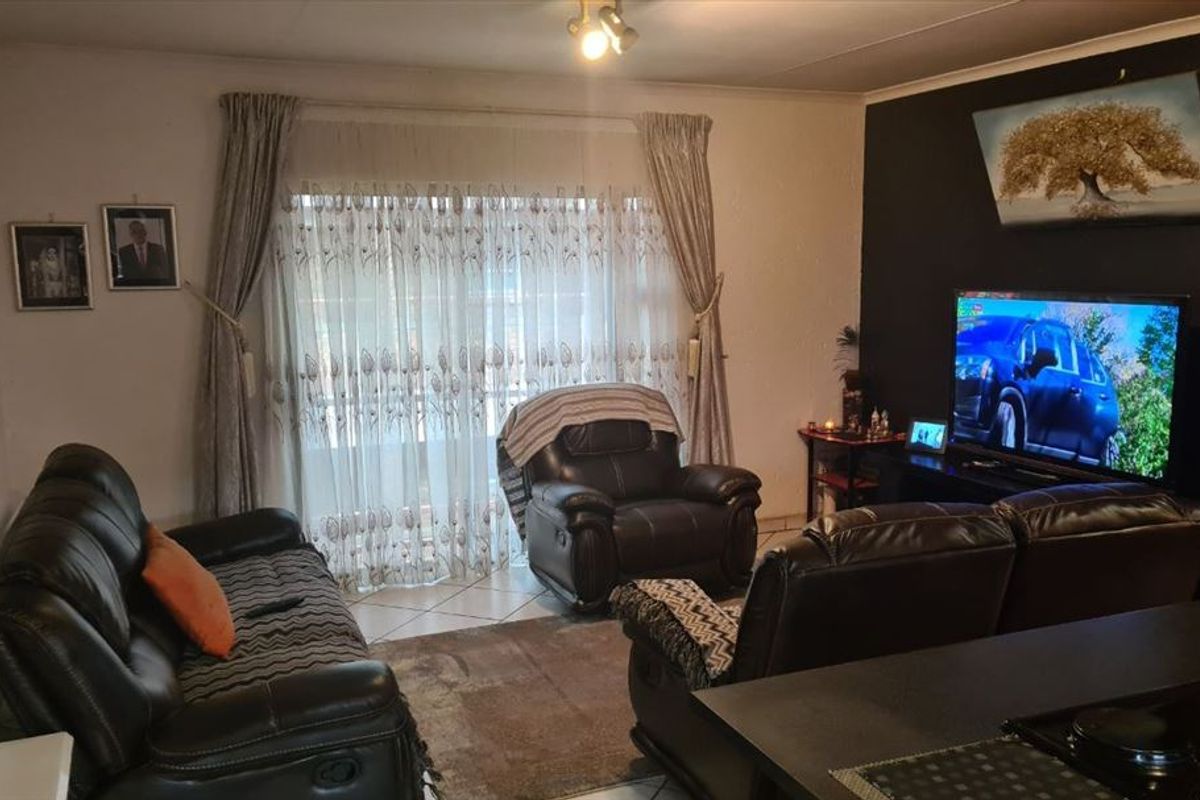 A living room area featuring tiled flooring and a sliding glass door providing natural light.