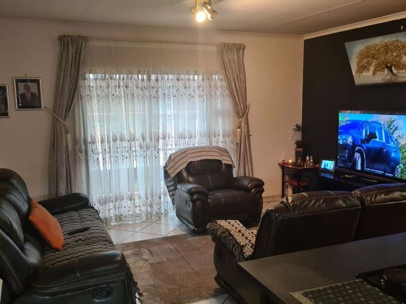 A living room area featuring tiled flooring and a sliding glass door providing natural light.