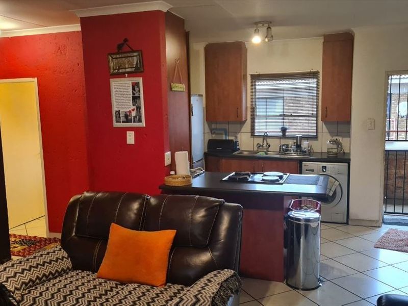 Open-plan living area featuring a compact kitchen with built-in cabinetry, gas hob, and direct access to an exterior balcony area.