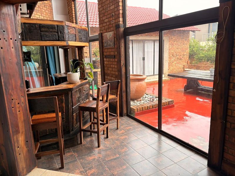 A rustic indoor bar area featuring exposed brick walls, tiled flooring, and large glass sliding doors that open onto a patio.