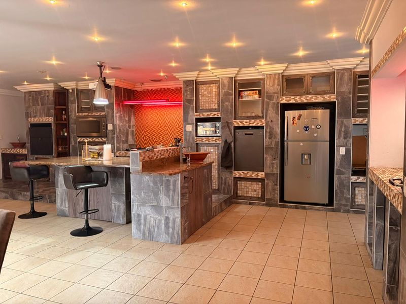 Spacious kitchen featuring extensive stone tile finishes, granite countertops, a central island, and integrated appliances with modern recessed lighting.