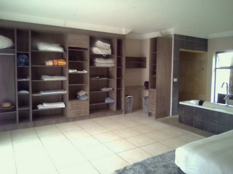 Spacious bedroom featuring extensive built-in cabinetry, tiled flooring, and an integrated en-suite bathtub area with modern tiling.