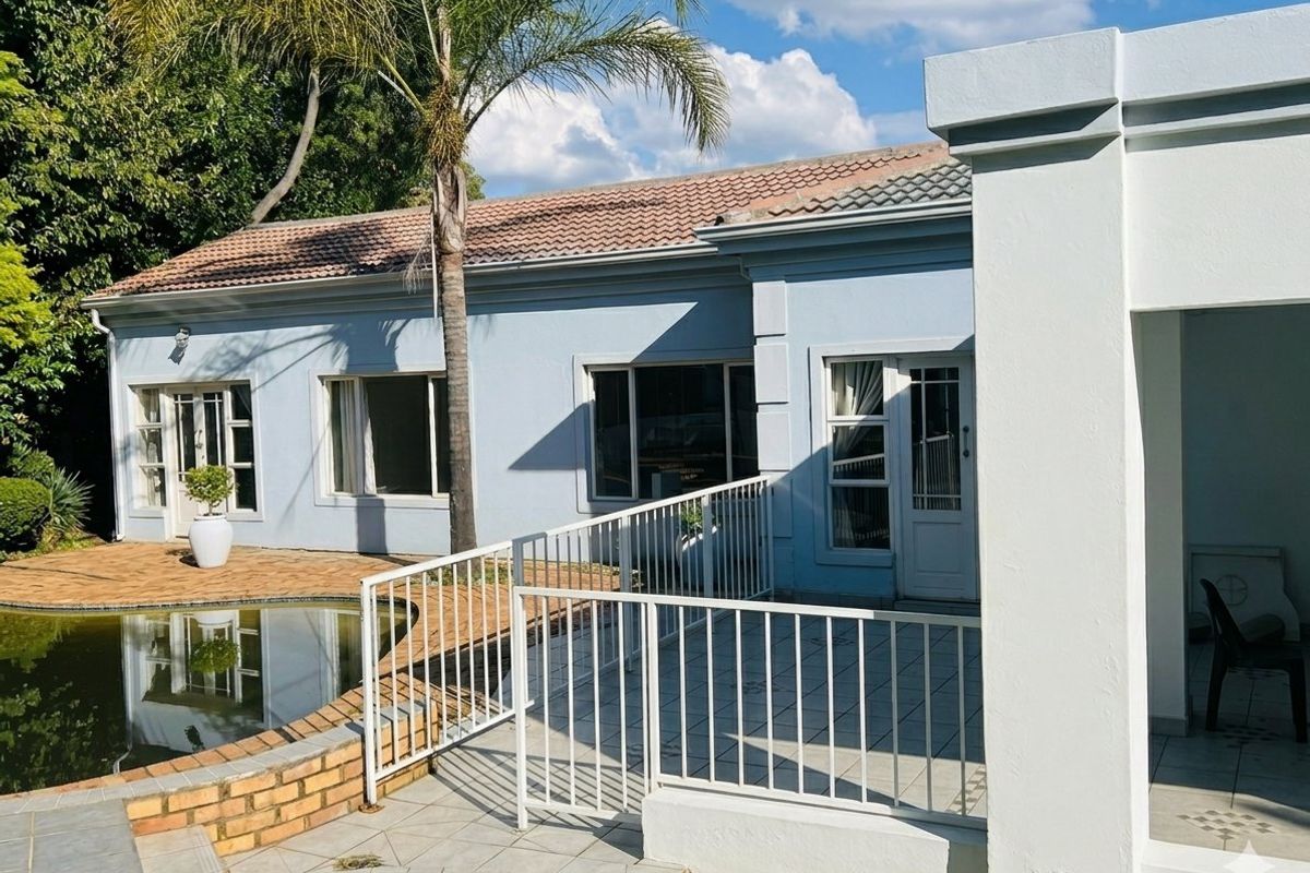 Rear exterior view featuring a tiled patio area, metal safety railing, and a swimming pool with a brick surround.
