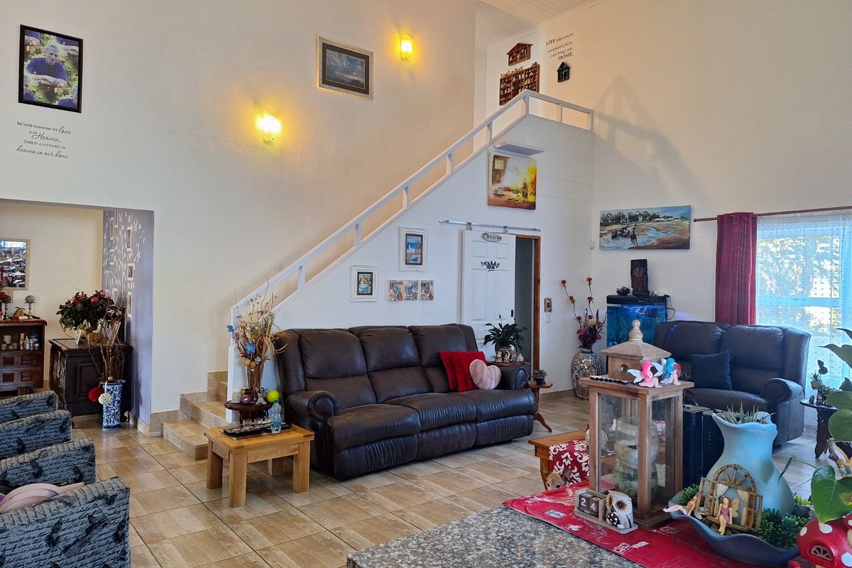 Spacious living room featuring high vaulted ceilings, tiled flooring, and a staircase leading to an upper level, with a sliding barn door entrance.