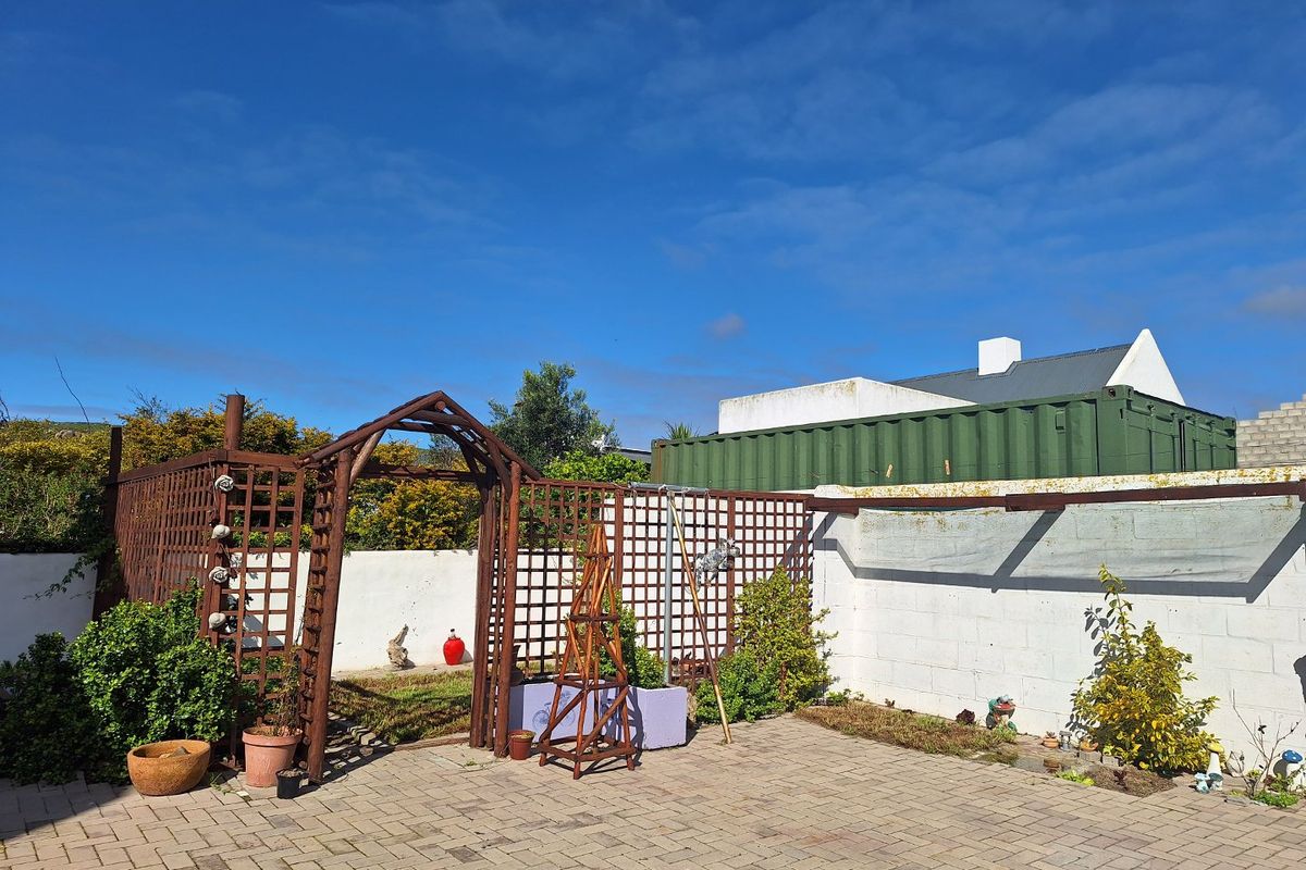 A rear courtyard featuring paved flooring, a timber garden arch, and a masonry boundary wall, offering a private outdoor space with potential for landscaping.
