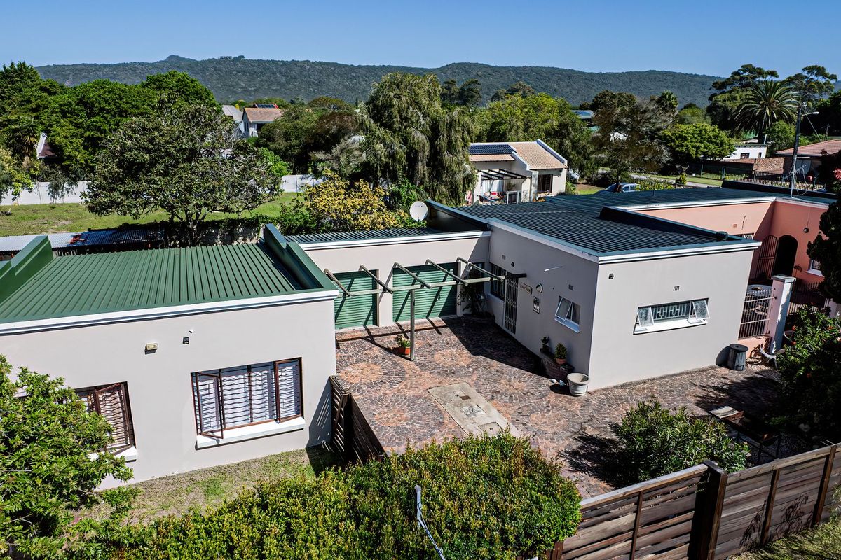 Aerial view of the property showing the main building structure, paved courtyard area, timber pergola, and surrounding garden landscape.