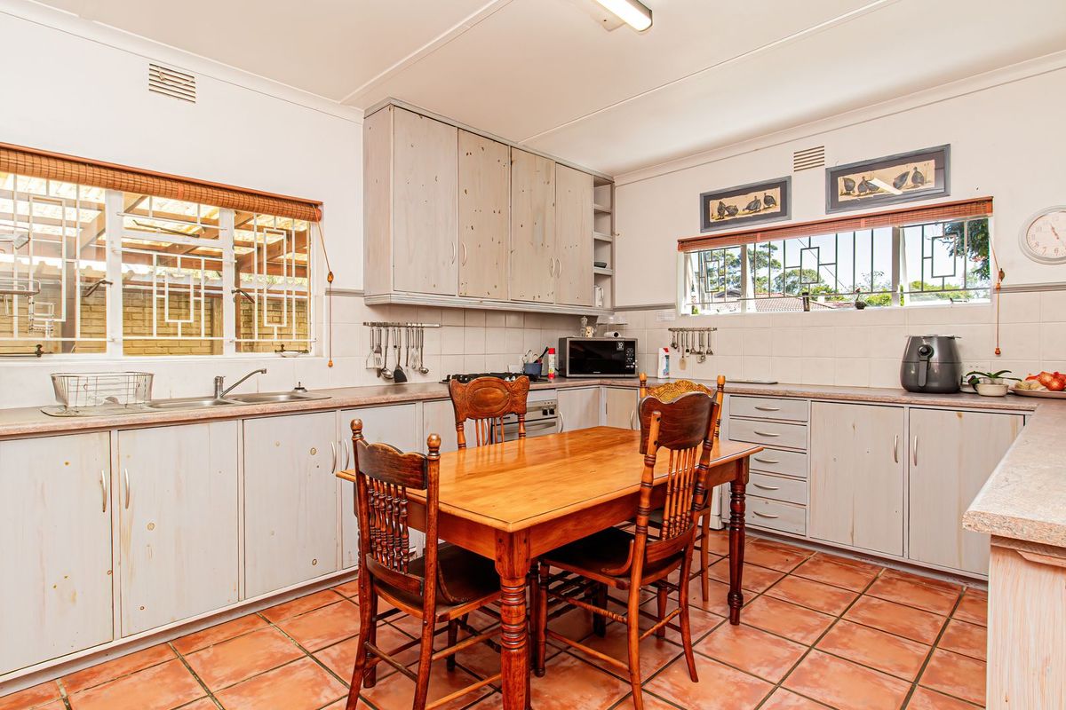 A functional kitchen featuring built-in cabinetry, laminate countertops, a double stainless steel sink, and ceramic tile flooring with a classic layout.
