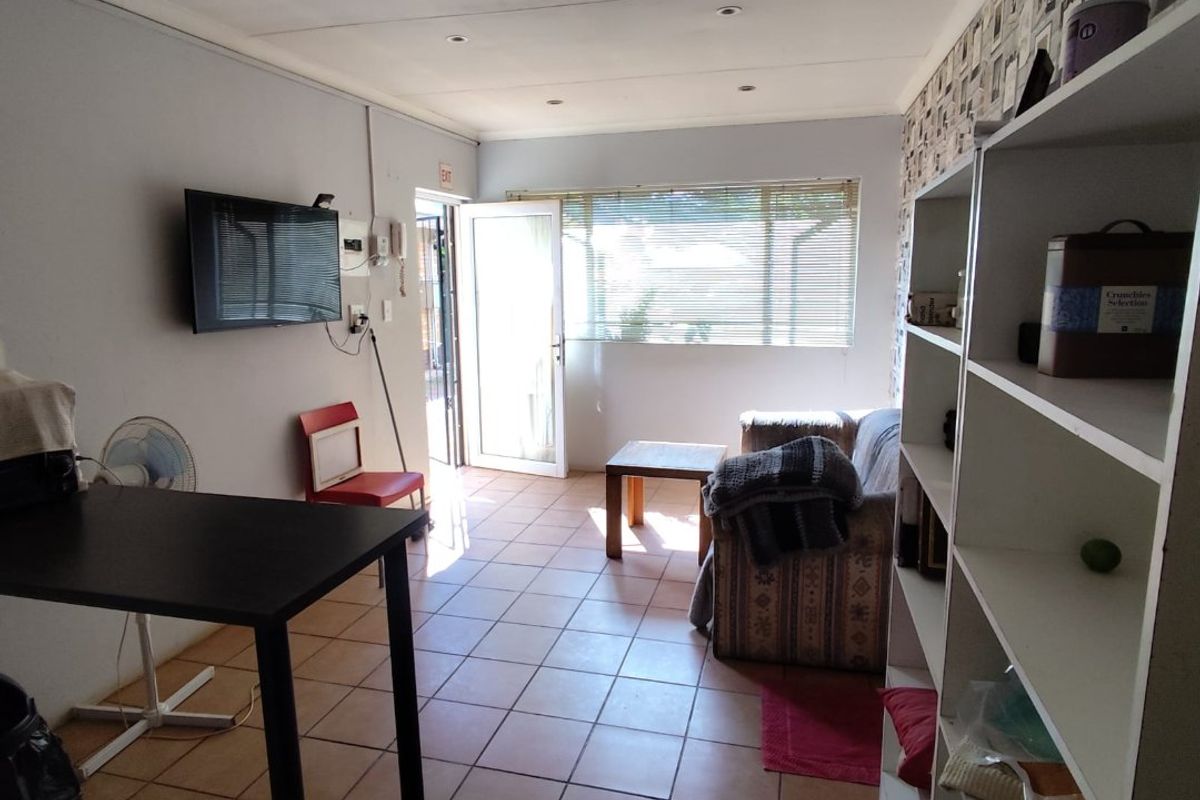 A living area featuring tiled flooring, recessed lighting, and direct access to the exterior through a glass-panelled door.