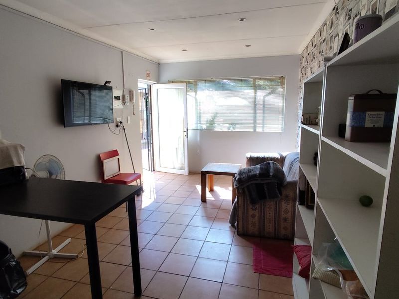 A living area featuring tiled flooring, recessed lighting, and direct access to the exterior through a glass-panelled door.