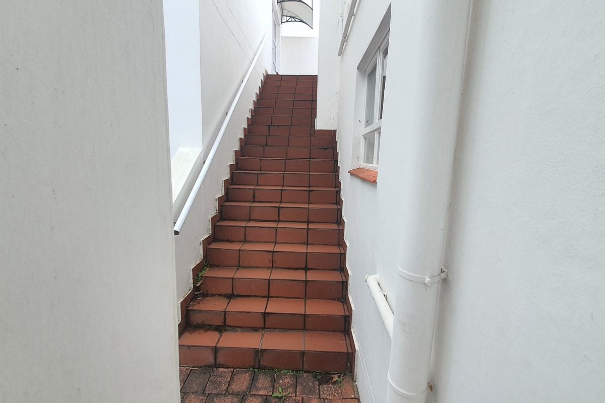An exterior staircase with tiled steps and a handrail providing access between levels of the townhouse.