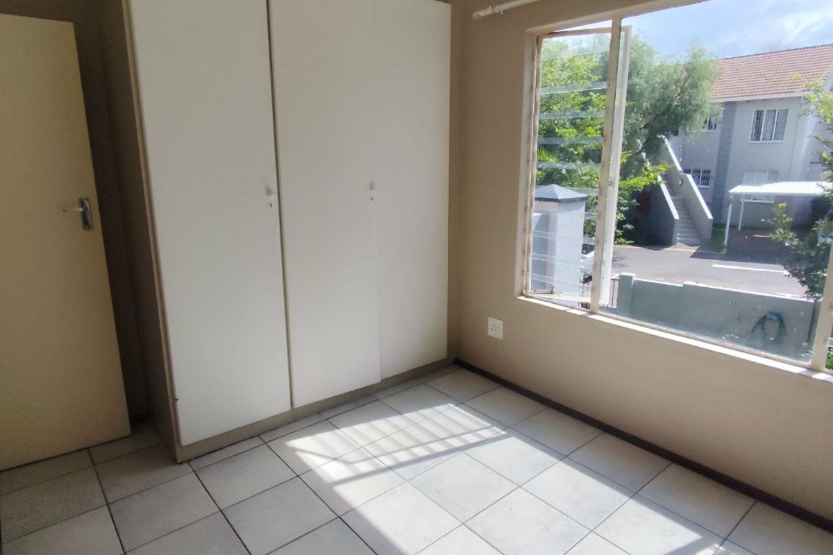 A bright, empty bedroom featuring tiled flooring and built-in cupboards, offering a clean canvas for personalization.