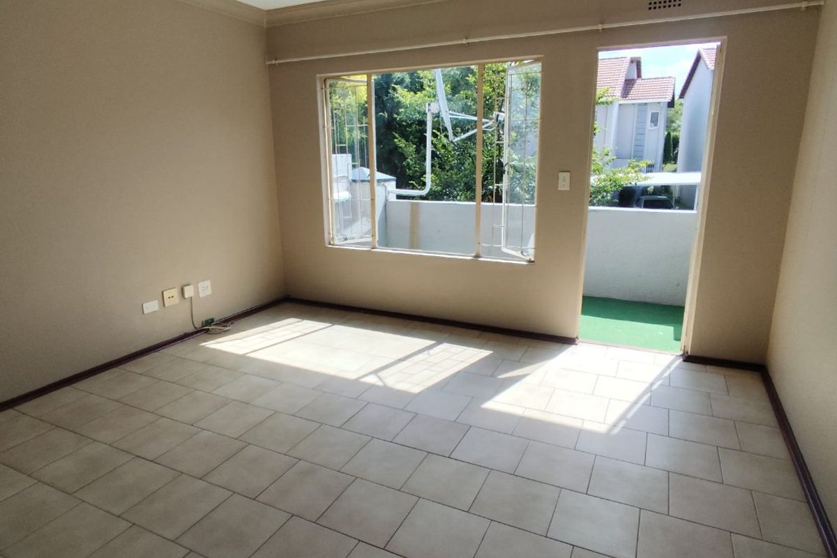 An empty living room featuring tiled flooring, neutral wall paint, and direct access to an outdoor balcony area.