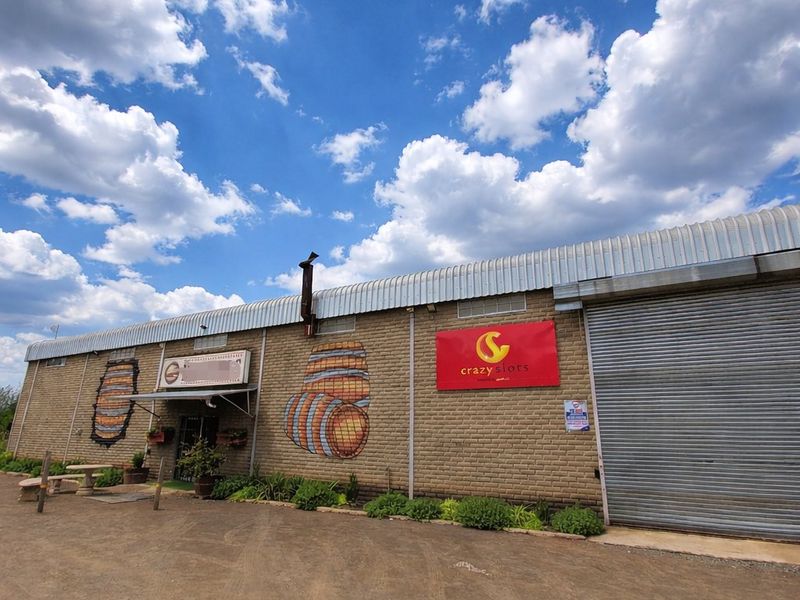 Front exterior view of a commercial warehouse building featuring a brick facade, large roller shutter door, and metal roofing.