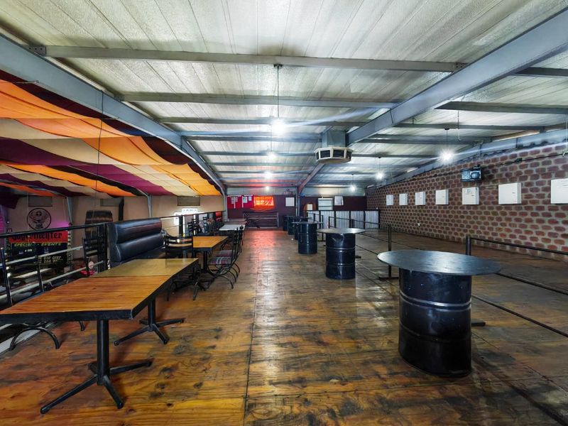 Spacious commercial clubhouse area featuring exposed steel roof trusses, brick wall detailing, and timber flooring, suitable for events or hospitality use.