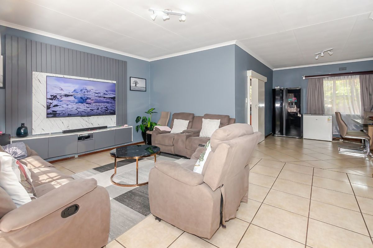 Spacious living area featuring tiled flooring, a modern feature wall with integrated media space, and recessed ceiling lighting.