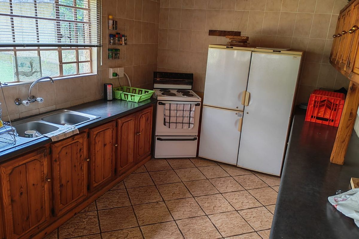A functional kitchen featuring wooden cabinetry, a double sink, tiled splashbacks, and an electric stove, offering a traditional farm-style aesthetic.