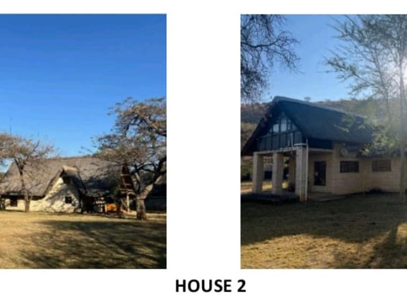 Exterior view of a farm-style house featuring a traditional thatch roof, masonry construction, and a spacious surrounding garden area.