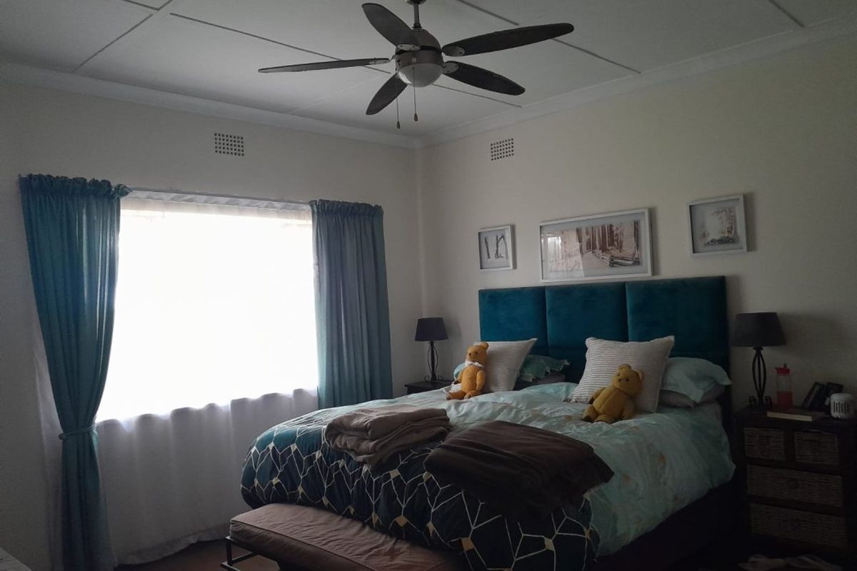 A well-maintained bedroom featuring a central ceiling fan and ventilation grilles, providing a comfortable and functional sleeping space.