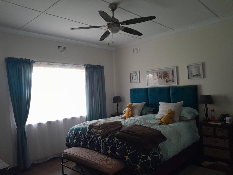 A well-maintained bedroom featuring a central ceiling fan and ventilation grilles, providing a comfortable and functional sleeping space.
