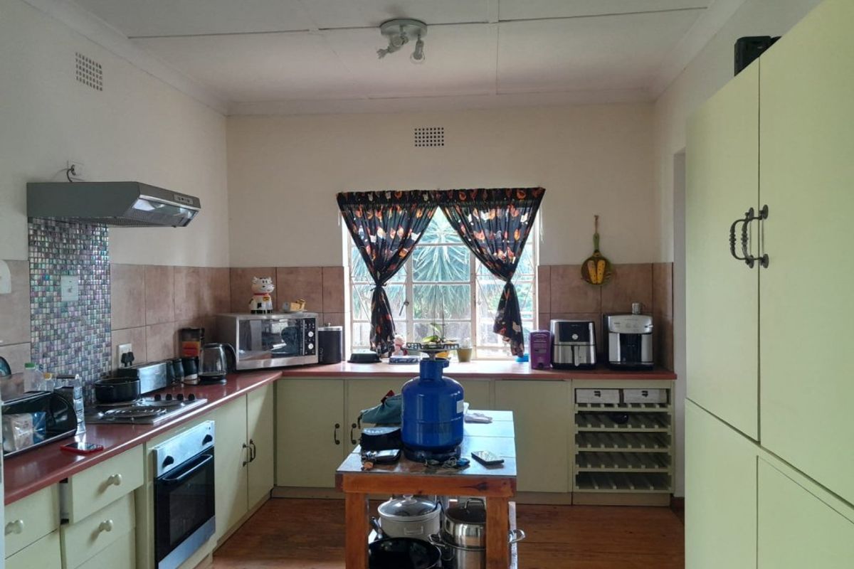 A functional kitchen featuring built-in cabinetry, a gas hob with extractor fan, integrated oven, and a dedicated wine rack with tiled splashback finishes.