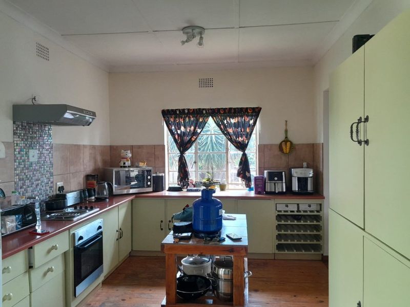 A functional kitchen featuring built-in cabinetry, a gas hob with extractor fan, integrated oven, and a dedicated wine rack with tiled splashback finishes.