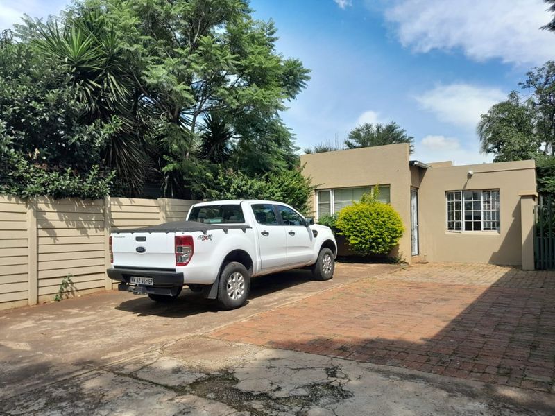 Front exterior view of the property featuring a paved driveway, precast boundary wall, and single-story building facade with aluminium window frames.