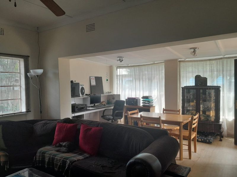 Open plan living and dining area featuring laminate flooring, a ceiling fan, and a built-in workspace nook.