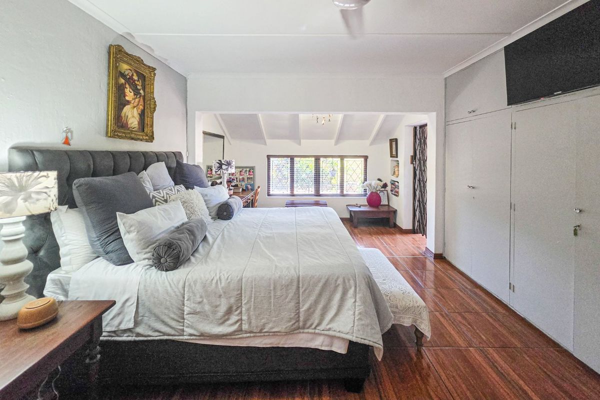 Spacious bedroom featuring tiled flooring, built-in cupboards, and an exposed beam ceiling, offering a comfortable and well-maintained living space.