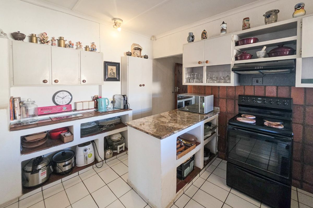 A functional kitchen featuring built-in cabinetry, stone countertops, a brick splashback, and ceramic floor tiles, offering potential for a modern renovation.