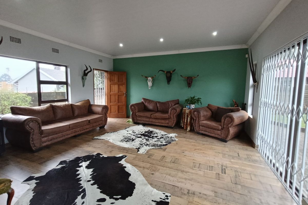 Spacious living room featuring timber-look floor tiles, recessed downlighting, and large windows with security gates, providing a bright and functional living space.