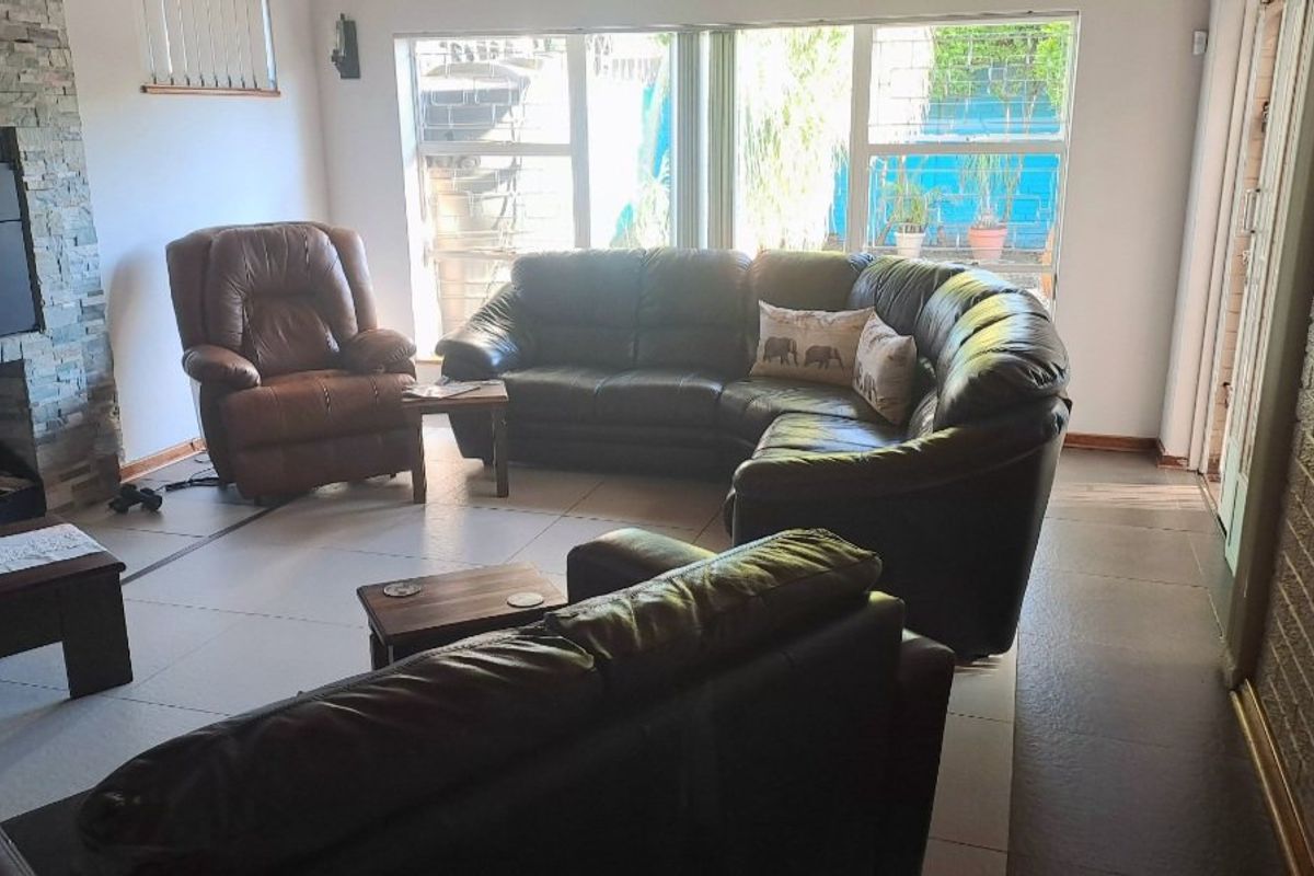 Spacious living room featuring a stone-clad fireplace, large windows for natural light, and tiled flooring throughout.