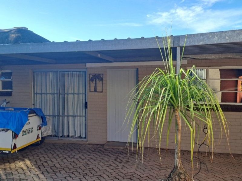 Front exterior view of the property featuring a brick facade, a covered carport area, and a paved driveway.