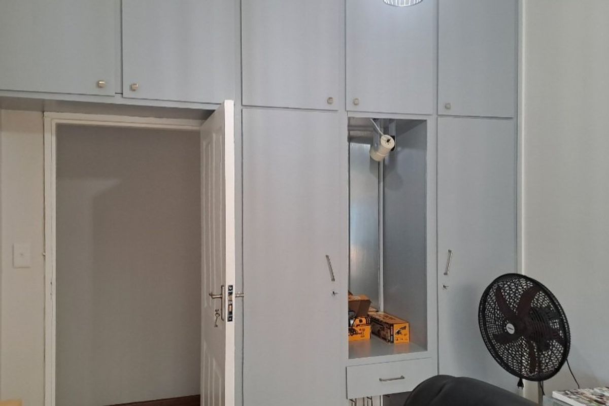 A bedroom featuring extensive built-in cupboards with overhead storage units and a standard internal door.