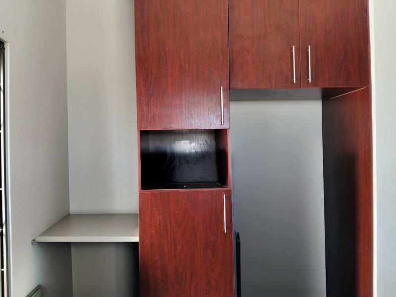 A kitchen area featuring built-in dark wood-look cabinetry and a small laminate countertop, providing functional storage and prep space.