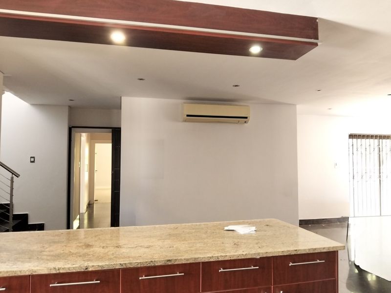 Spacious open-plan living area featuring a large granite kitchen island, recessed ceiling lighting, and a wall-mounted air conditioning unit.