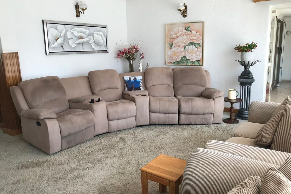 A comfortable living room featuring carpeted flooring, wall-mounted lighting, and timber ceiling detailing, providing a functional and traditional living space.
